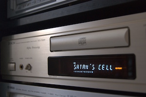 Un lecteur CD doré sur lequel s’affiche le texte « Satan’s Cell »